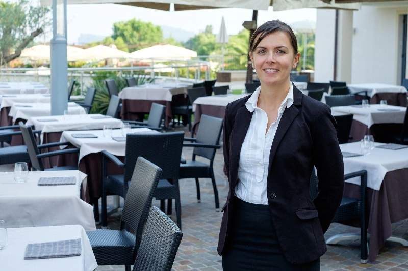 A woman standing in front of an outdoor restaurant.